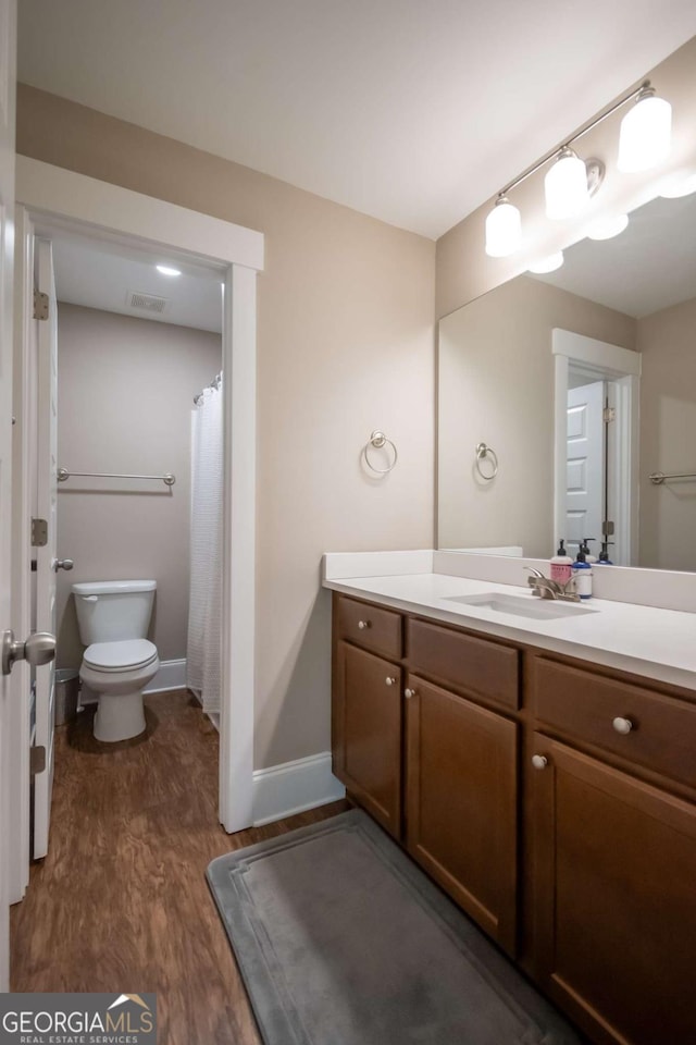 full bath with wood finished floors, toilet, vanity, and baseboards