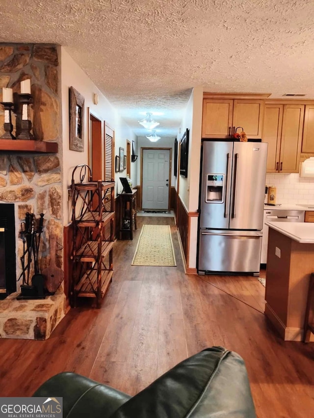 hall with wood-type flooring, a textured ceiling, and wainscoting