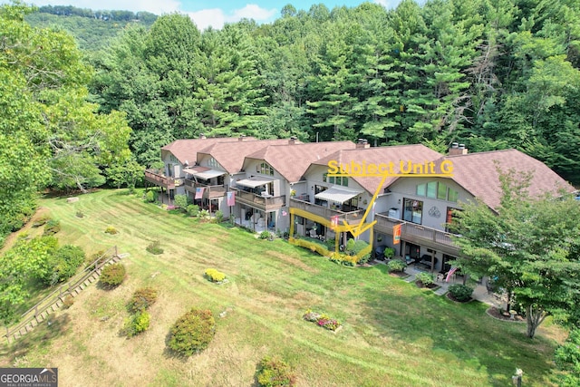 aerial view of property and surrounding area featuring a heavily wooded area