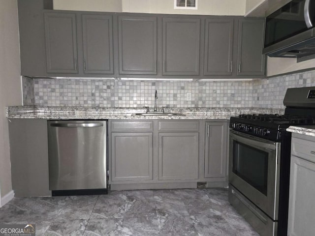 6136 Holiday Blvd, Forest Park, GA 30297 - kitchen with stainless steel appliances, a sink, gray cabinets, backsplash, and light stone countertops