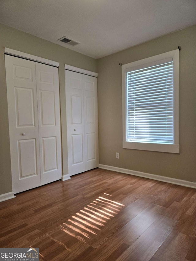 6136 Holiday Blvd, Forest Park, GA 30297 - unfurnished bedroom featuring multiple closets, wood finished floors, and baseboards