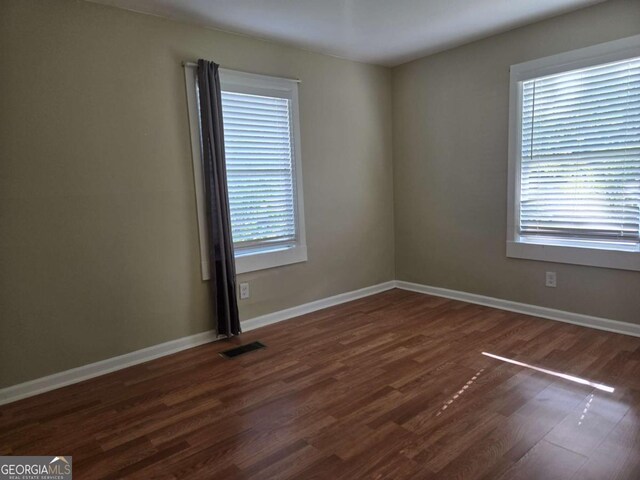 6136 Holiday Blvd, Forest Park, GA 30297 - empty room featuring dark wood-style flooring, plenty of natural light, and baseboards