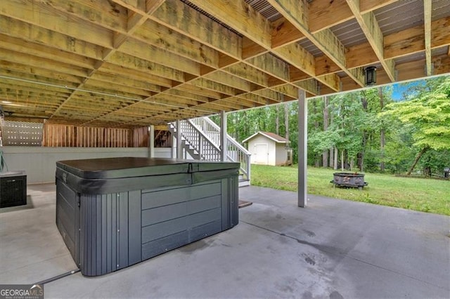 view of patio / terrace featuring a hot tub, stairway, a shed, an outdoor structure, and an outdoor fire pit