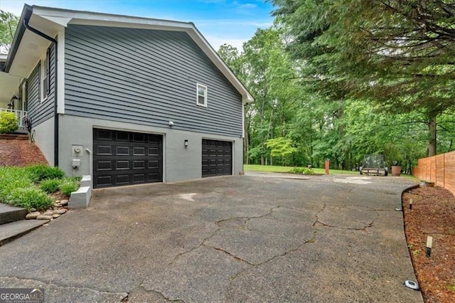 view of property exterior with an attached garage, driveway, and stucco siding