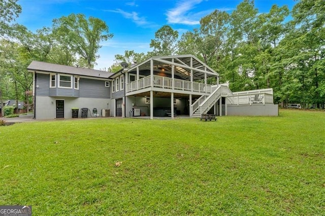 rear view of house with a wooden deck, stairs, and a lawn