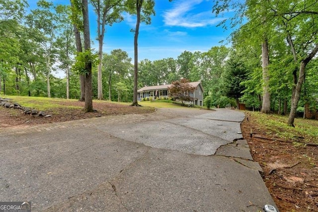 view of front of house with asphalt driveway and view of wooded area