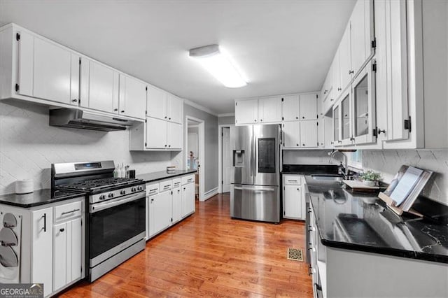 kitchen with appliances with stainless steel finishes, under cabinet range hood, a sink, white cabinets, and light wood-style flooring