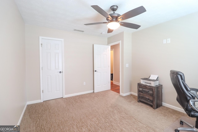 carpeted office space with ceiling fan and baseboards