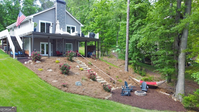 view of front of property featuring stairway, french doors, a fire pit, and a chimney
