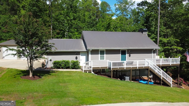 rear view of house featuring a wooden deck, stairs, a lawn, metal roof, and a chimney