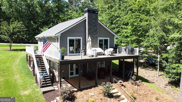 rear view of house featuring stairs, a deck, a lawn, french doors, and a chimney