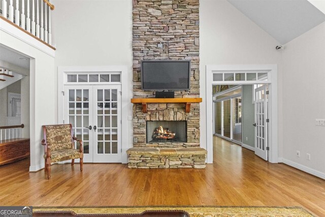 1221 Cosby Cir, Greensboro, GA 30642 - living area featuring french doors, high vaulted ceiling, wood finished floors, a stone fireplace, and baseboards