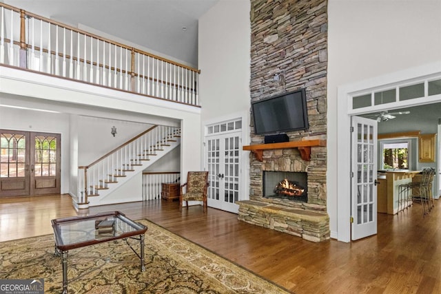 1221 Cosby Cir, Greensboro, GA 30642 - living room featuring french doors, a high ceiling, wood finished floors, a fireplace, and ceiling fan