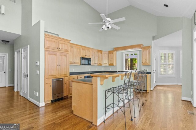 1221 Cosby Cir, Greensboro, GA 30642 - kitchen featuring black microwave, light brown cabinets, high vaulted ceiling, ceiling fan, and a kitchen breakfast bar