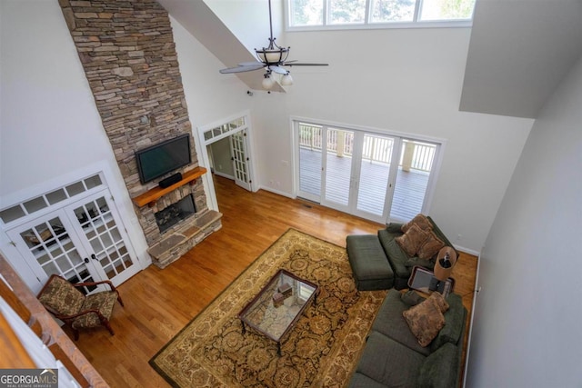 1221 Cosby Cir, Greensboro, GA 30642 - living area featuring ceiling fan, french doors, a high ceiling, wood finished floors, and a stone fireplace