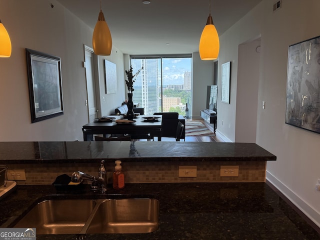 kitchen featuring a sink, baseboards, and hanging light fixtures