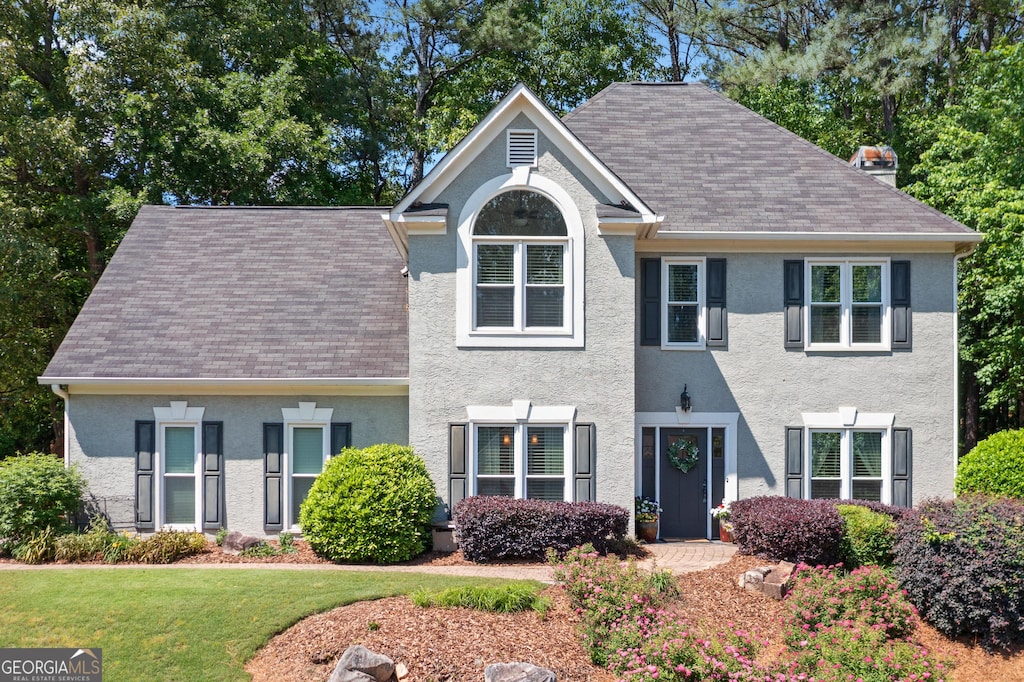 2009 Westside Ln, Woodstock, GA 30189 - view of front facade with stucco siding, a front lawn, roof with shingles, and a chimney