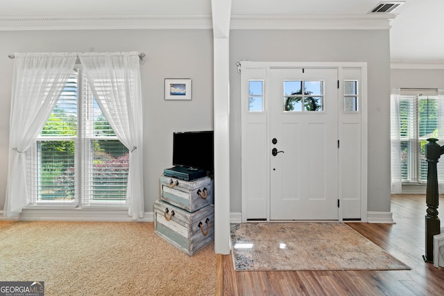 entryway with crown molding, healthy amount of natural light, wood finished floors, and baseboards