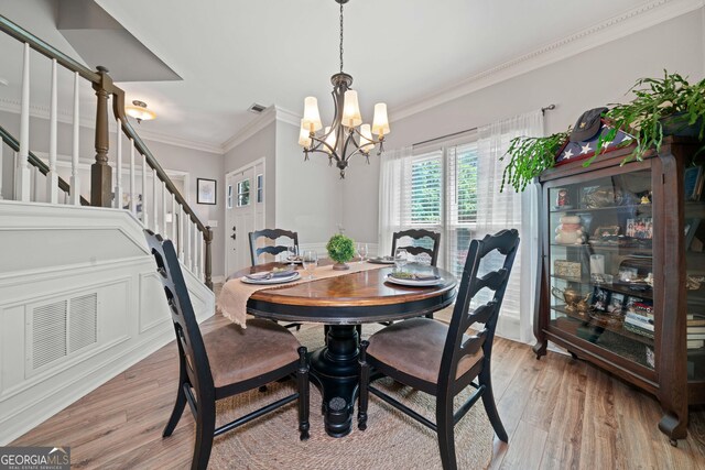 dining room featuring a chandelier, stairway, ornamental molding, and light wood finished floors
