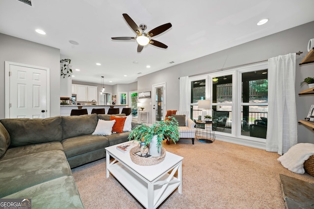 living area with a ceiling fan, plenty of natural light, recessed lighting, and light carpet