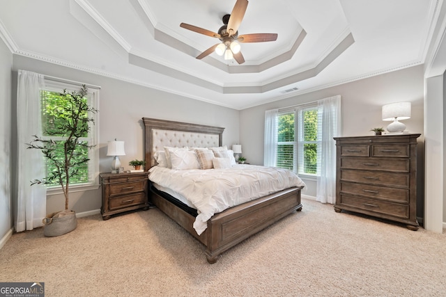 bedroom with light colored carpet, ornamental molding, a tray ceiling, ceiling fan, and baseboards