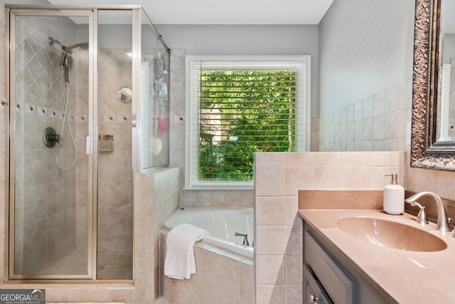 full bathroom with a stall shower, a bath, vanity, and tile walls
