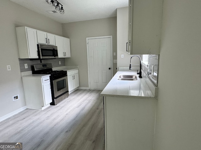 2711 Teal Landing Dr, Morrow, GA 30260 - kitchen with appliances with stainless steel finishes, a sink, light wood-type flooring, backsplash, and white cabinets