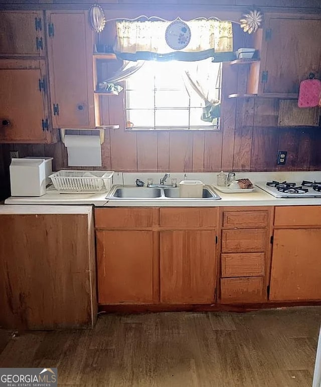 kitchen featuring a sink, dark wood-style flooring, light countertops, and white gas cooktop