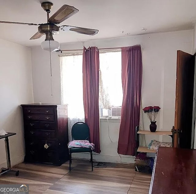 living area featuring ceiling fan, wood finished floors, and cooling unit