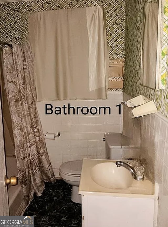 bathroom featuring toilet, vanity, marble look tiles, tile walls, and wallpapered walls