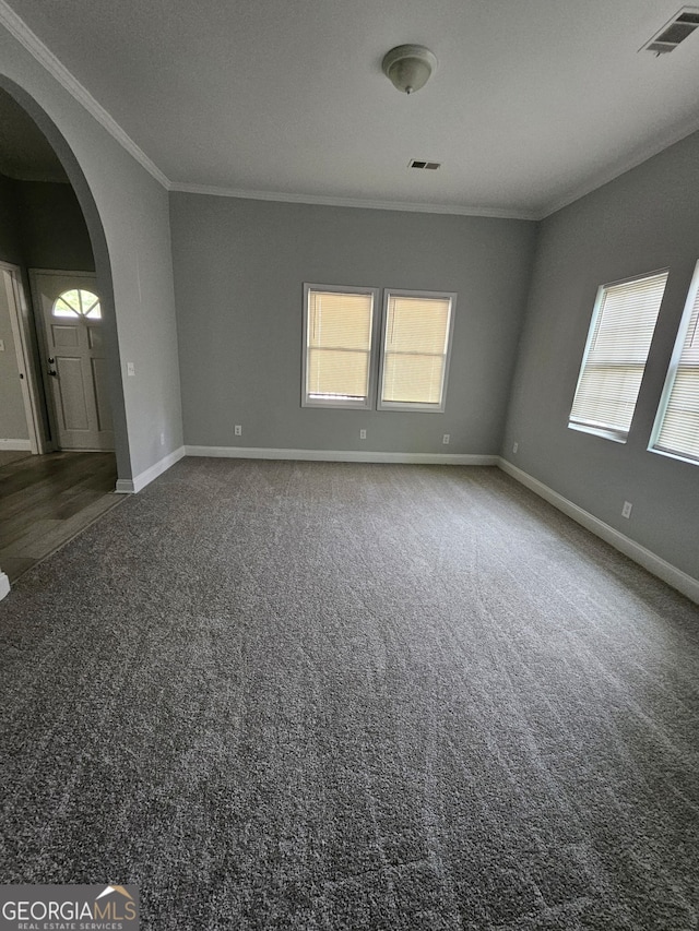 carpeted empty room with arched walkways, ornamental molding, healthy amount of natural light, and baseboards