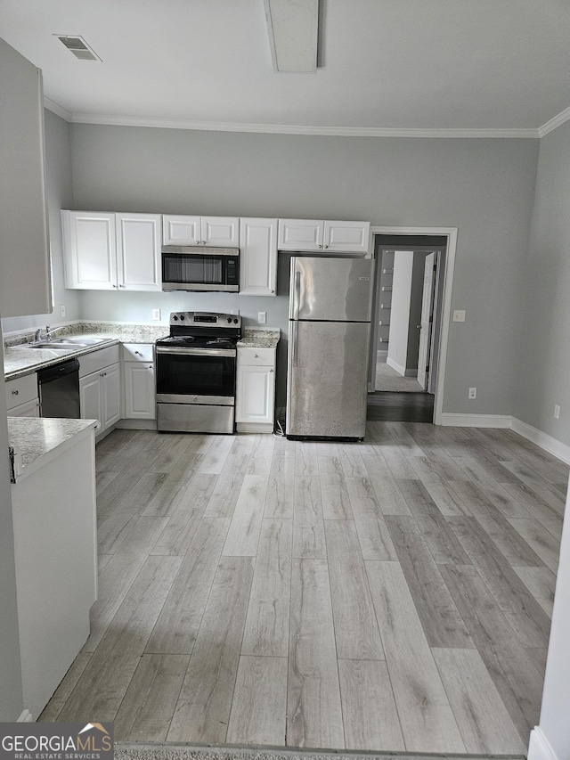 kitchen featuring stainless steel appliances, crown molding, light wood-style flooring, light countertops, and white cabinetry