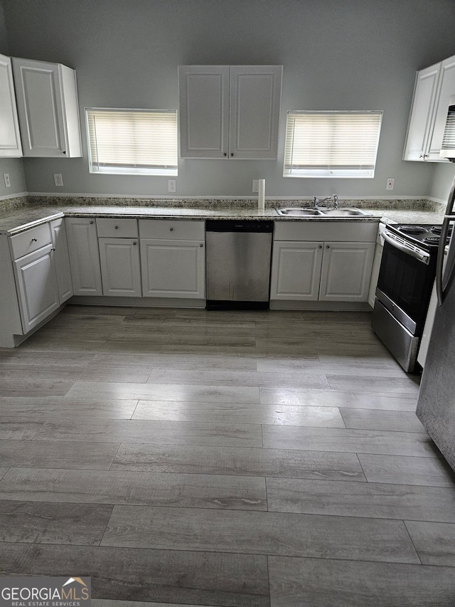 kitchen featuring stainless steel appliances, a sink, light wood finished floors, and white cabinets