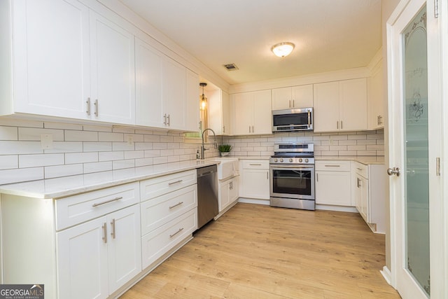 10 Queens Ct, Sharpsburg, GA 30277 - kitchen with appliances with stainless steel finishes, white cabinets, decorative backsplash, and light wood-type flooring