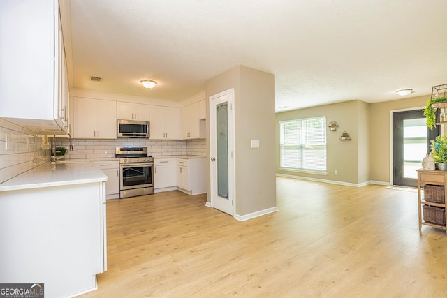 10 Queens Ct, Sharpsburg, GA 30277 - kitchen with appliances with stainless steel finishes, backsplash, light countertops, light wood finished floors, and white cabinets