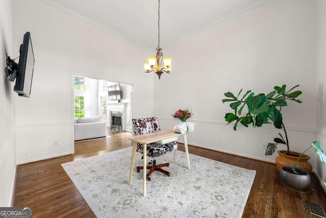 office area with ornamental molding, a chandelier, a fireplace, wood finished floors, and baseboards
