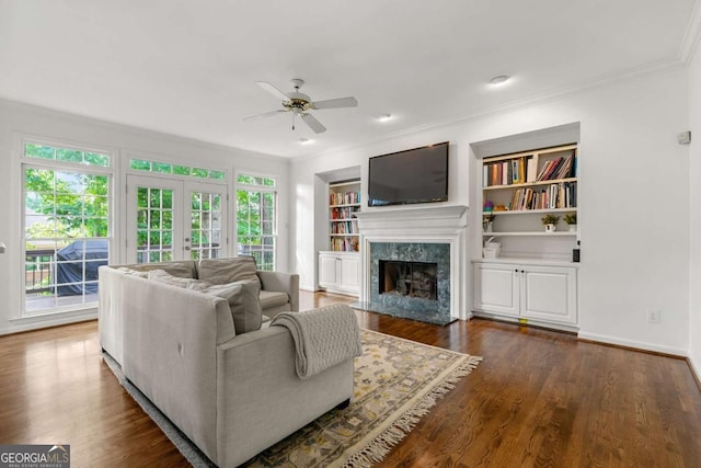 living area with ceiling fan, ornamental molding, plenty of natural light, a high end fireplace, and dark wood finished floors