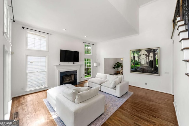 living area featuring wood finished floors, a high end fireplace, recessed lighting, baseboards, and a high ceiling