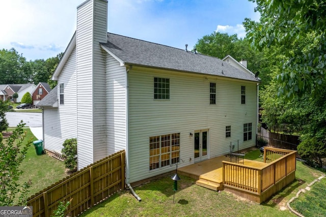 rear view of house featuring a wooden deck, a chimney, and roof with shingles
