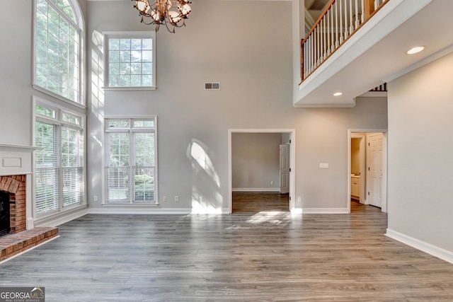 2049 Mclain Rd NW, Acworth, GA 30101 - unfurnished living room with a high ceiling, a brick fireplace, a chandelier, baseboards, and healthy amount of natural light