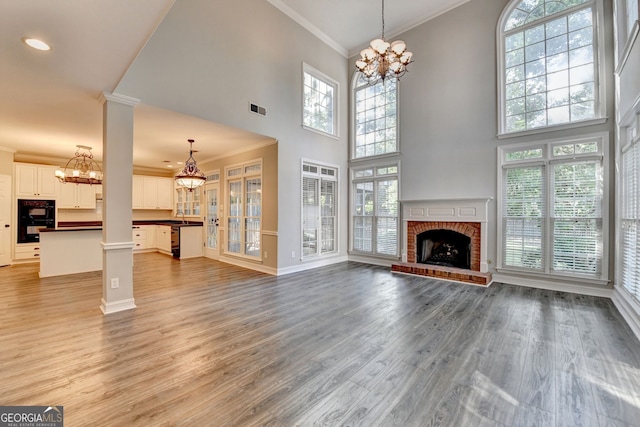 2049 Mclain Rd NW, Acworth, GA 30101 - unfurnished living room with a chandelier, ornamental molding, a fireplace, light wood finished floors, and a towering ceiling