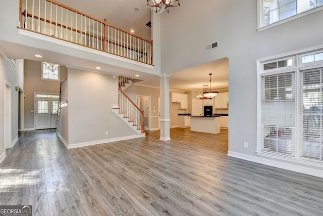 2049 Mclain Rd NW, Acworth, GA 30101 - unfurnished living room with a towering ceiling, a chandelier, stairway, light wood finished floors, and baseboards