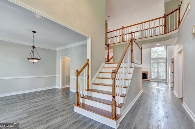 2049 Mclain Rd NW, Acworth, GA 30101 - stairs featuring a high ceiling, wood finished floors, baseboards, a brick fireplace, and ornamental molding