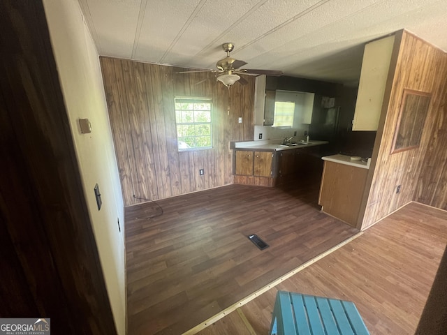 491 Cavender Creek Rd, Carrollton, GA 30116 - kitchen featuring wood walls, ceiling fan, dark wood-type flooring, brown cabinetry, and light countertops