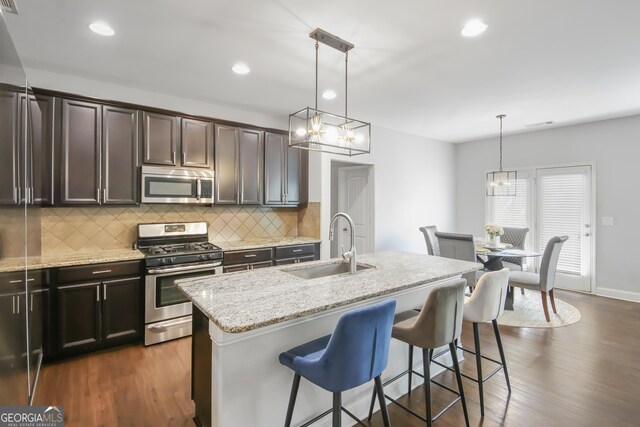 1720 Grant Ct, Braselton, GA 30517 - kitchen with appliances with stainless steel finishes, a sink, tasteful backsplash, light stone counters, and a kitchen island with sink