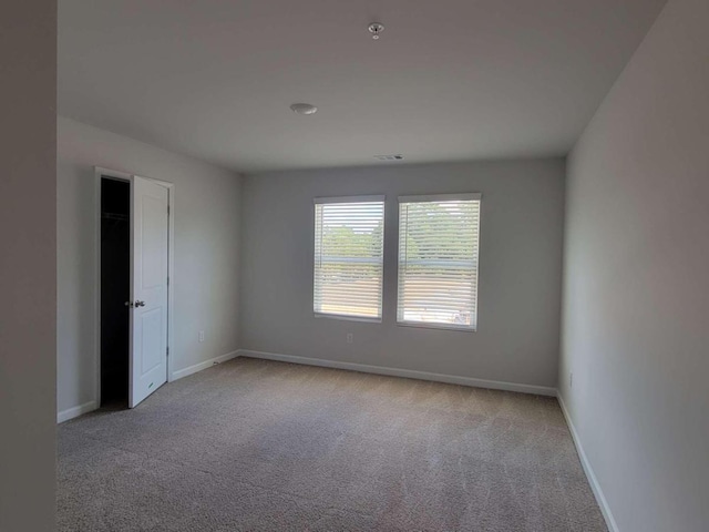 unfurnished room featuring carpet flooring, baseboards, and fire sprinkler in ceiling