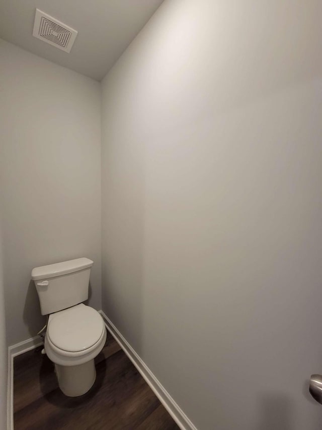 bathroom with baseboards, wood finished floors, and toilet
