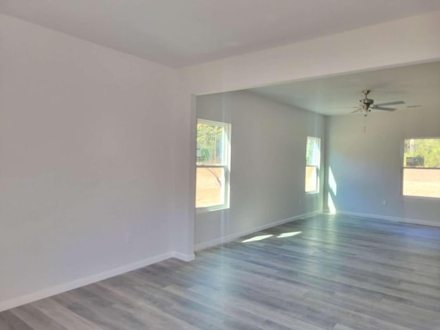 unfurnished room featuring baseboards, healthy amount of natural light, wood finished floors, and a ceiling fan