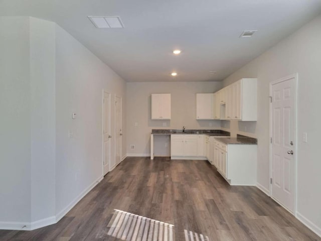 kitchen featuring dark wood-type flooring, recessed lighting, baseboards, white cabinets, and a sink