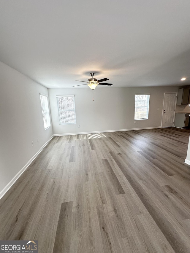 unfurnished living room featuring baseboards, ceiling fan, and wood finished floors